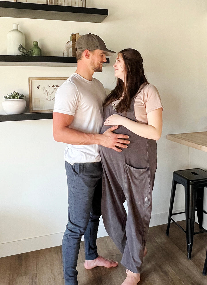 Image of man standing with wife, his hand on her belly. Man is wearing the Men's Organic DAD Joggers in Charcoal.