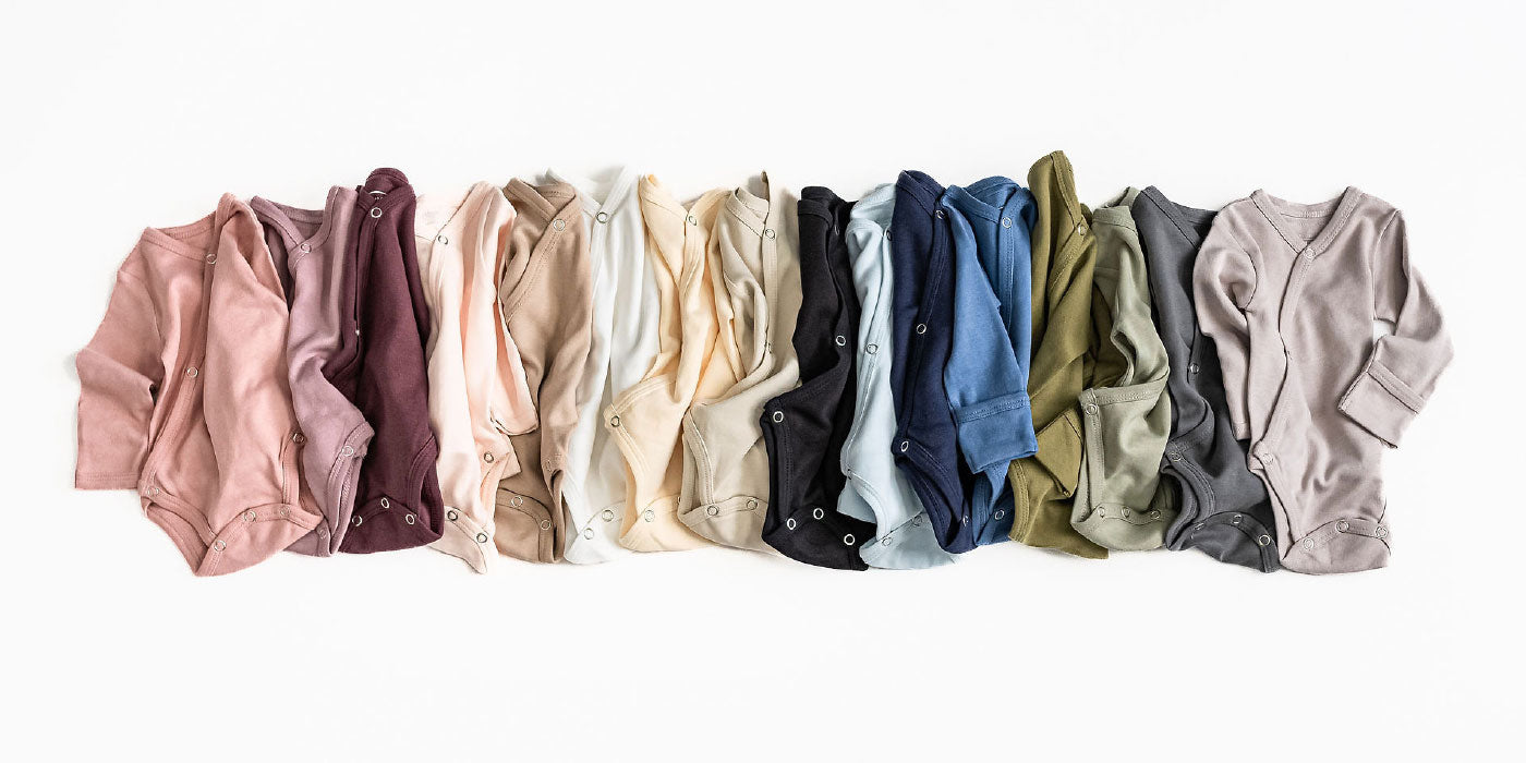 An assortment of colors of the organic kimono bodysuit style.