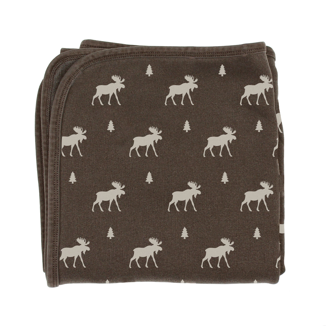 Folded brown blanket with white moose and tree pattern on a white background