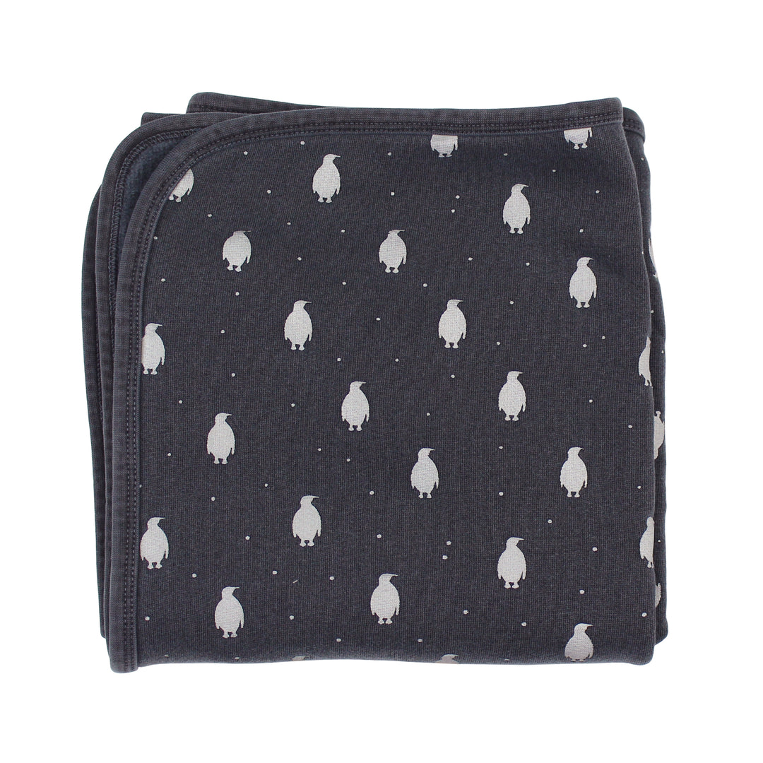 Folded dark gray blanket with white penguin pattern on a white background