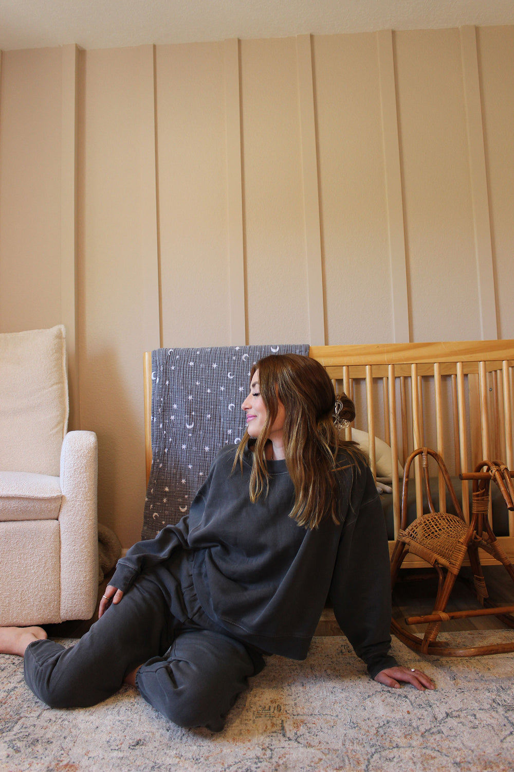 Woman sitting on the floor in a room with beige walls and furniture.