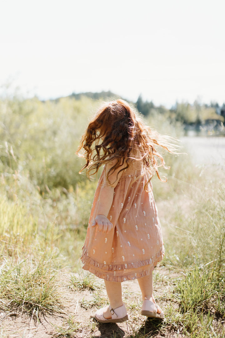 Child wearing Kids' Organic Muslin Summer Dress in Adobe Seahorse.