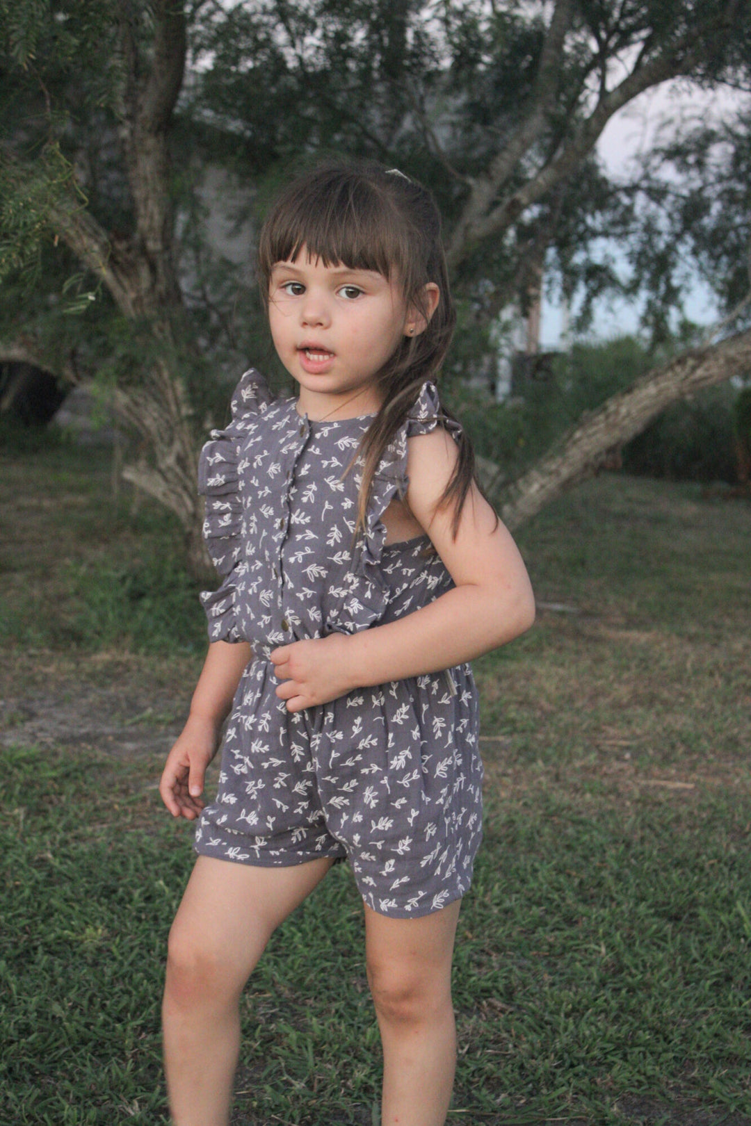 Child wearing a Kids' Organic Muslin Ruffle Jumper in Dusk Leaves