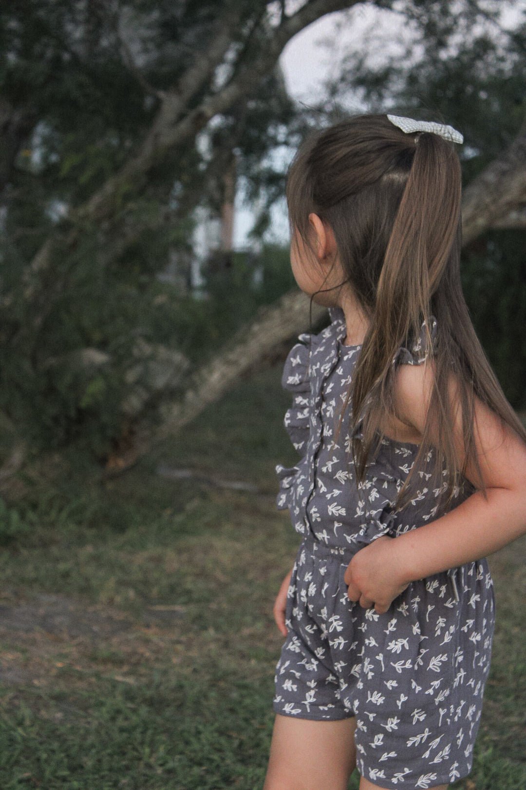 Child wearing a Kids' Organic Muslin Ruffle Jumper in Dusk Leaves