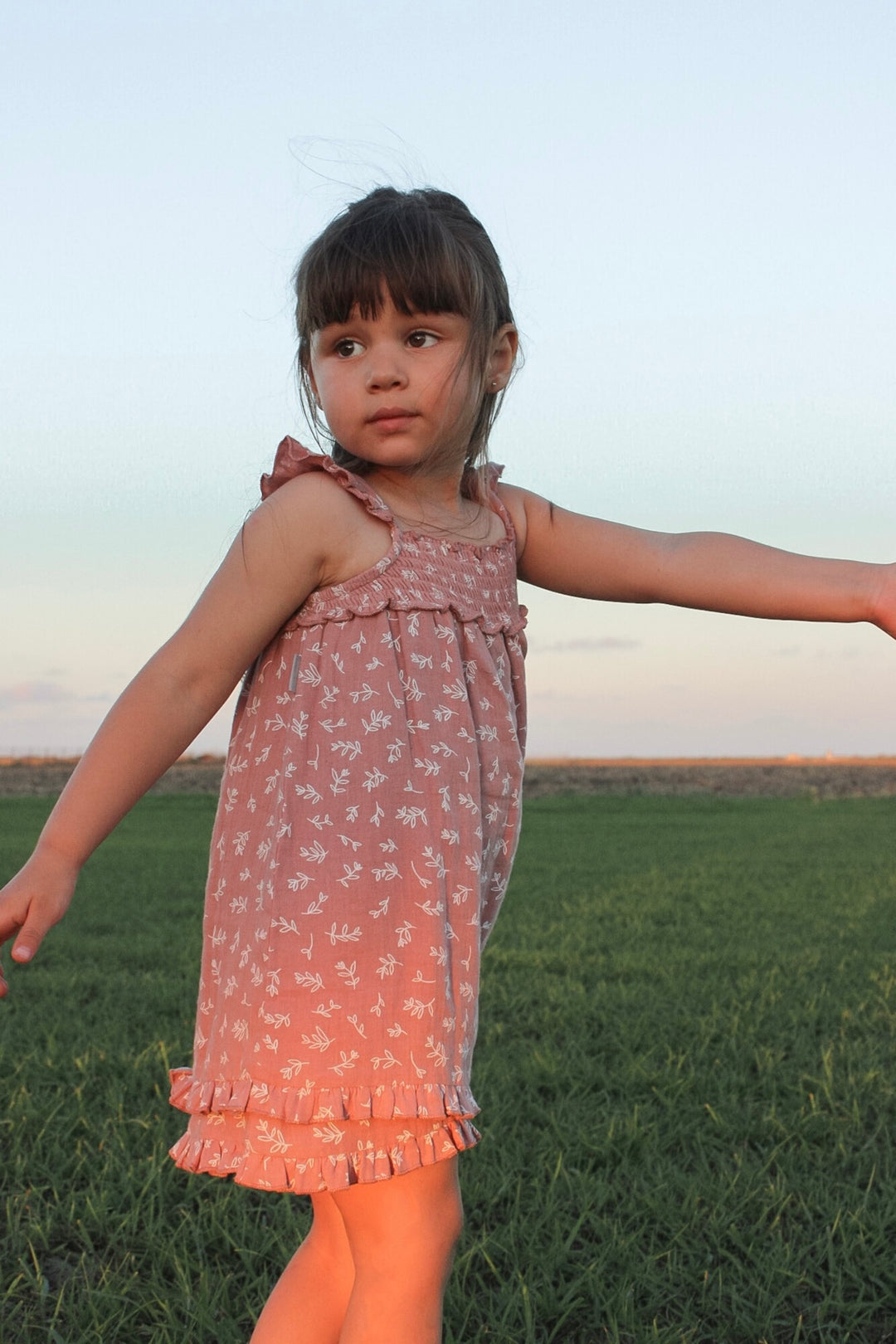 Child wearing Kids' Organic Muslin Summer Dress in Desert Rose Leaves.