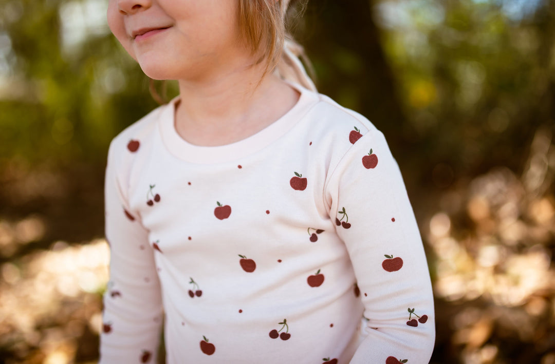 Child wearing Kids' Organic L/Sleeve PJ Set in Cherry Apple.