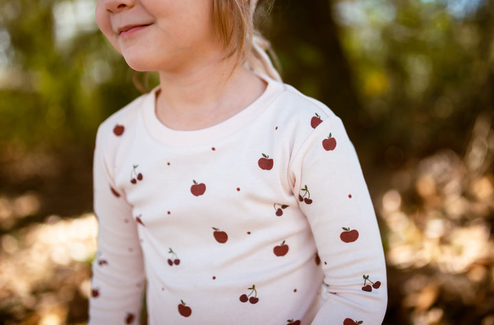 Child wearing Kids' Organic L/Sleeve PJ Set in Cherry Apple.