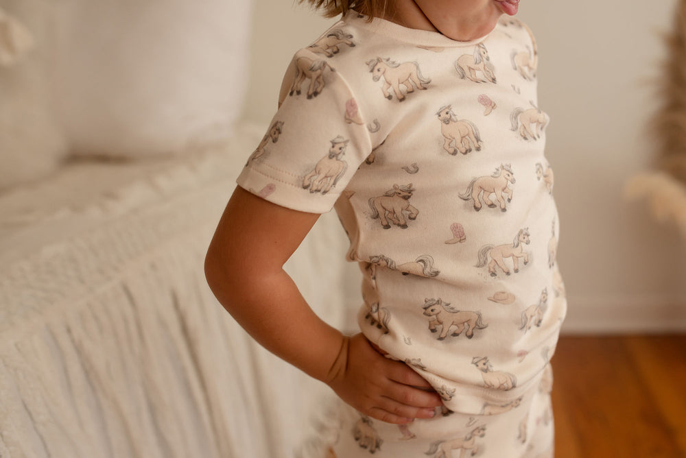 Child wearing Kids' Organic Short-Sleeve PJ Set in Blush Boots.