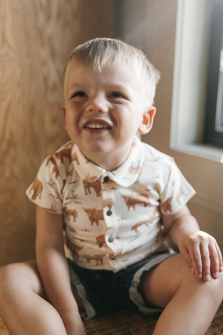 Child wearing Kids' Organic Button-Up S/Sleeve in Highland Cow.