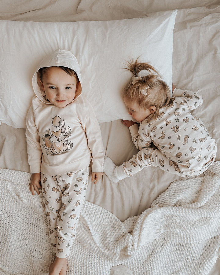 Two children in matching pajamas lying on a bed.