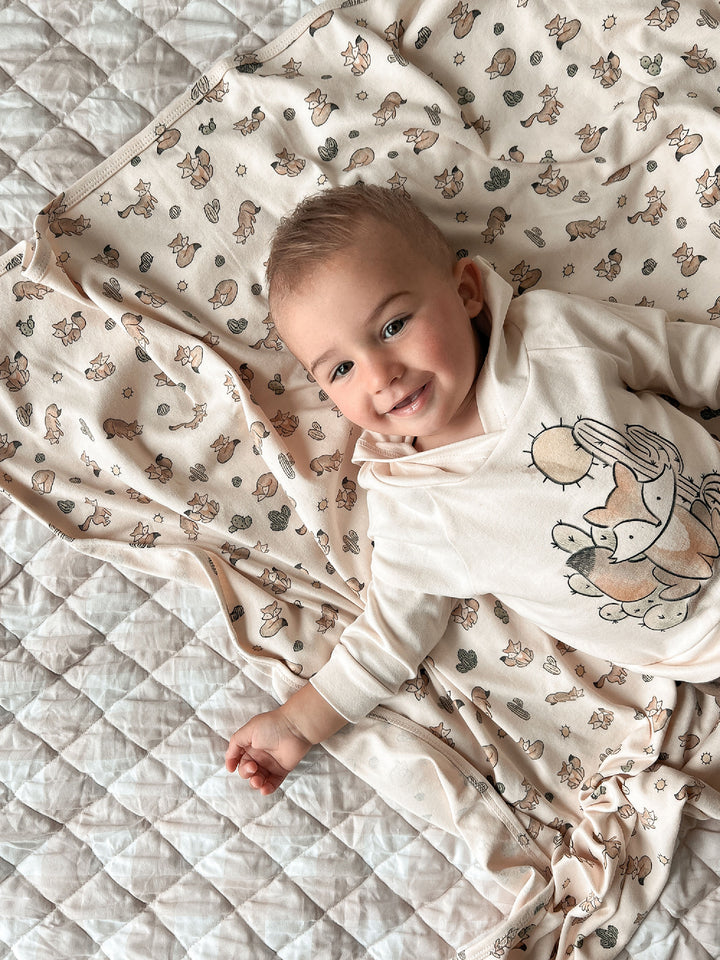 Baby lying on a patterned quilt with a soft focus background