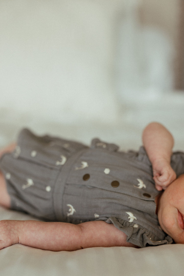 Child wearing Organic Muslin Ruffle Bodysuit in Moonstone Dolphin.