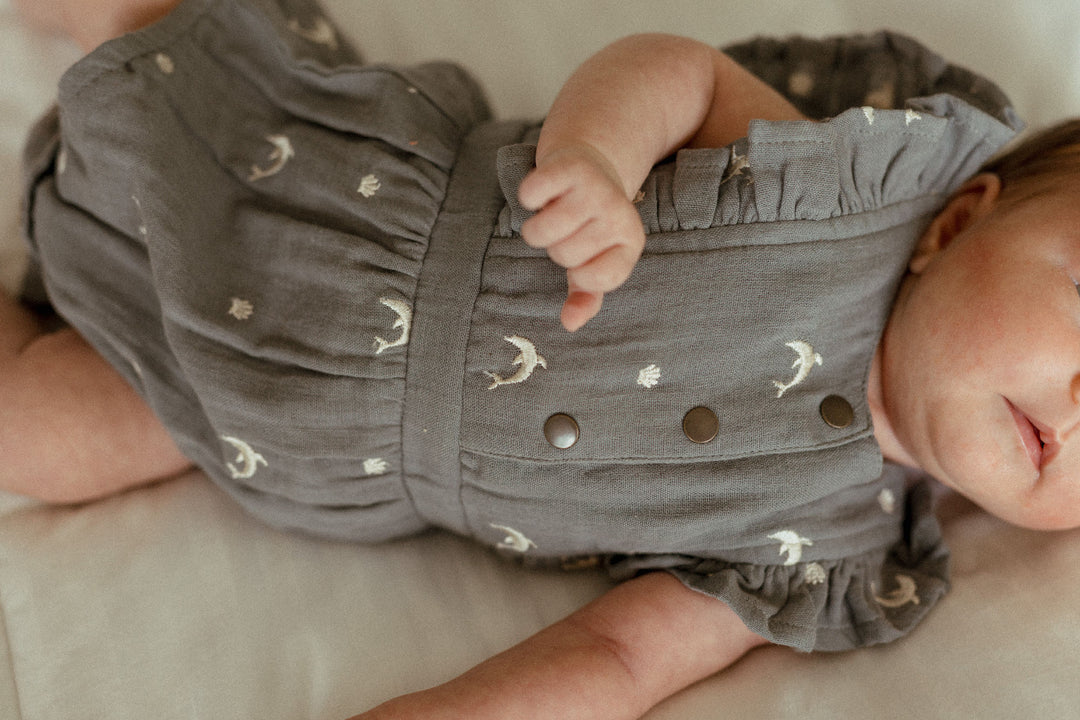Child wearing Organic Muslin Ruffle Bodysuit in Moonstone Dolphin.