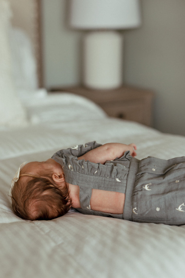 Child wearing Organic Muslin Ruffle Bodysuit in Moonstone Dolphin.