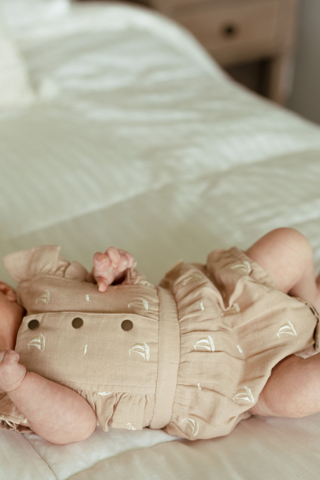 Child wearing Organic Muslin Ruffle Bodysuit in Oatmeal Sailboat.