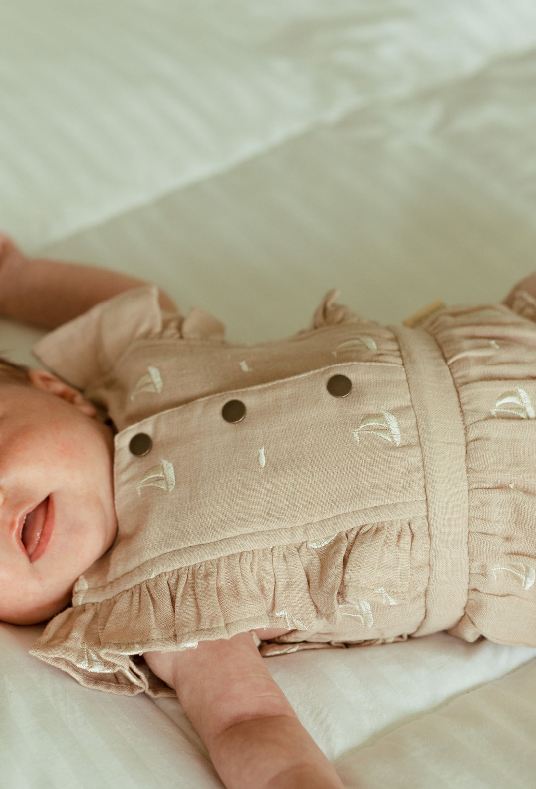 Child wearing Organic Muslin Ruffle Bodysuit in Oatmeal Sailboat.