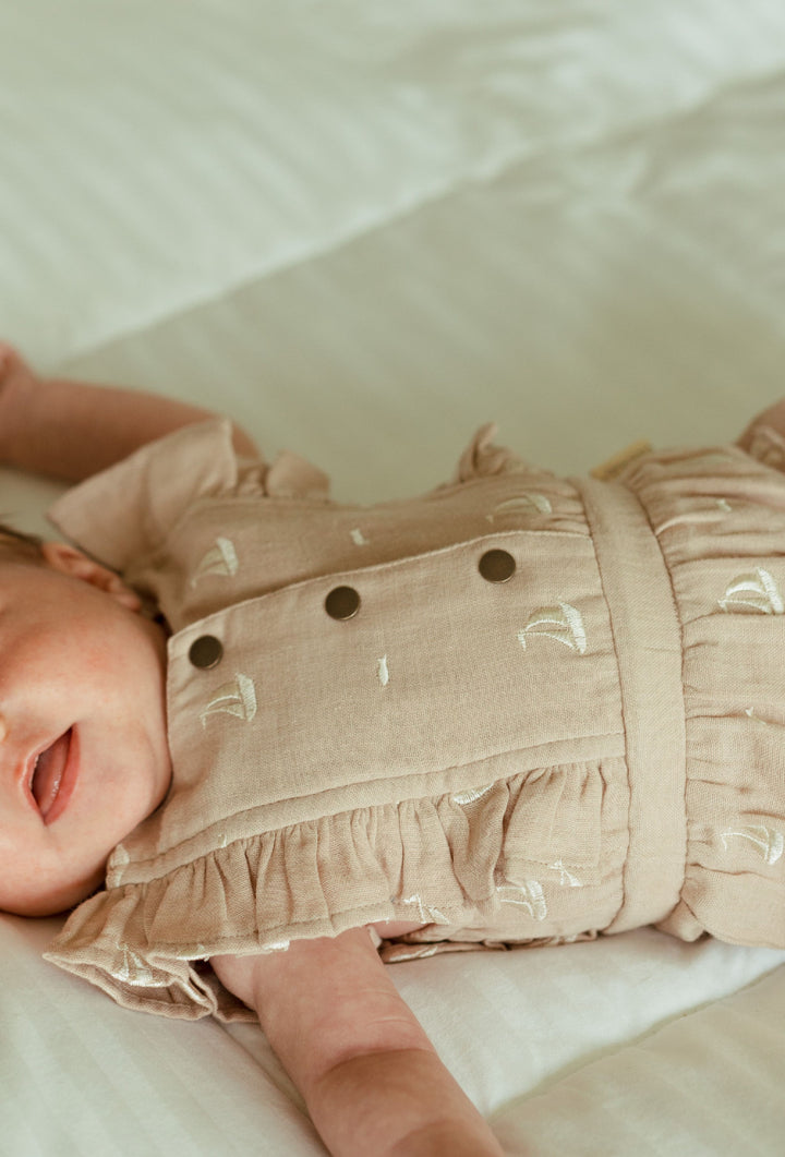 Child wearing Organic Muslin Ruffle Bodysuit in Oatmeal Sailboat.