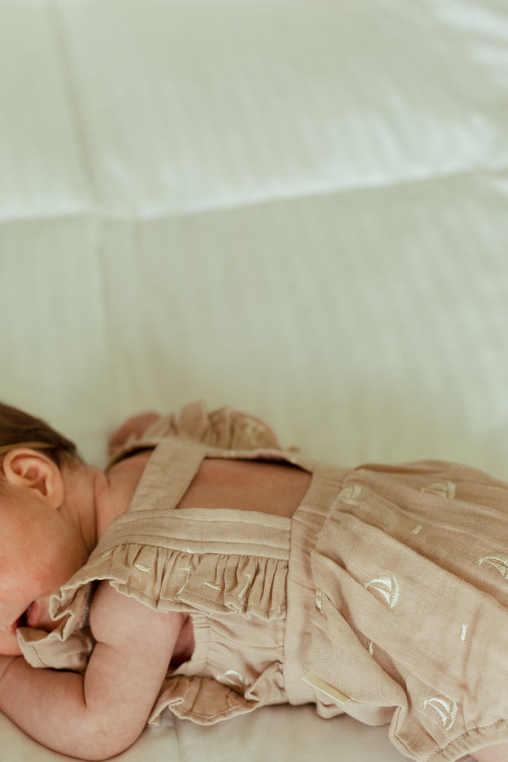 Child wearing Organic Muslin Ruffle Bodysuit in Oatmeal Sailboat.