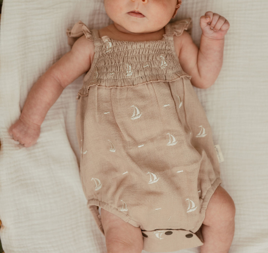 Child wearing Organic Muslin Sleeveless Bodysuit in Oatmeal Sailboat.