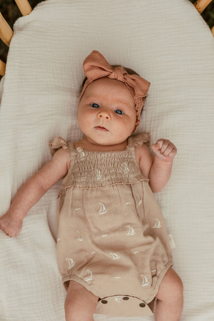Child wearing Organic Muslin Sleeveless Bodysuit in Oatmeal Sailboat.