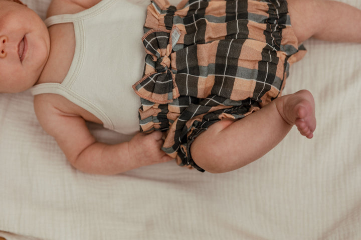 Child wearing Organic Muslin Ruffle Bloomer in Adobe Chia Plaid.