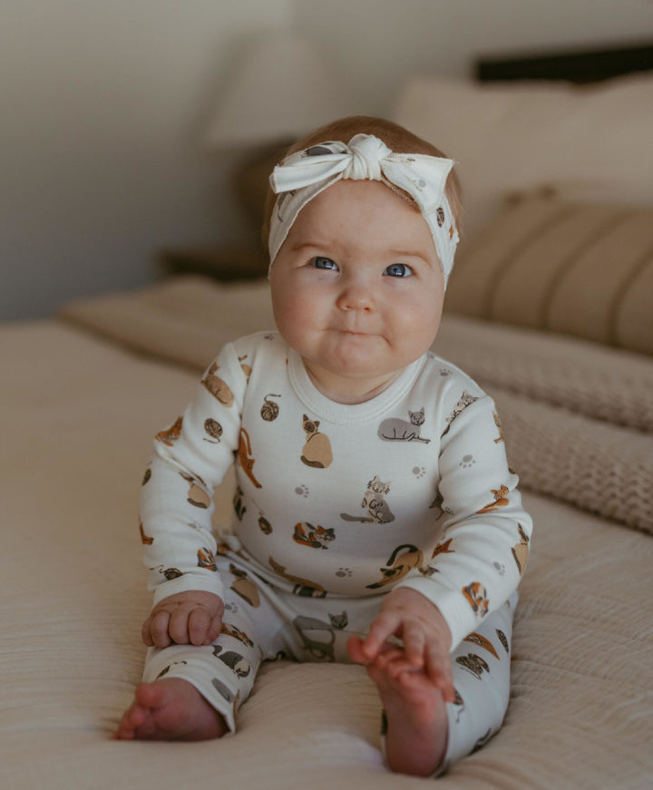 Child wearing Organic Long-Sleeve Bodysuit in 9 Lives.