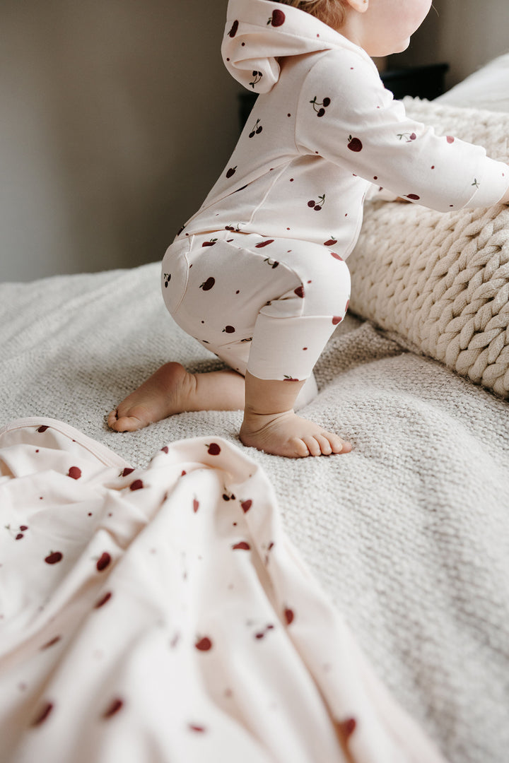 Child wearing Organic Hooded Zipper Romper in Cherry Apple.