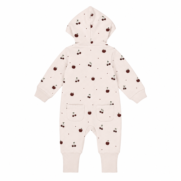 A baby hooded one-piece romper in a warm off-white/cream color, decorated with a small all-over print of dark brown cherries and tiny dark dots. The romper features long sleeves, ribbed cuffs, and two front patch pockets.