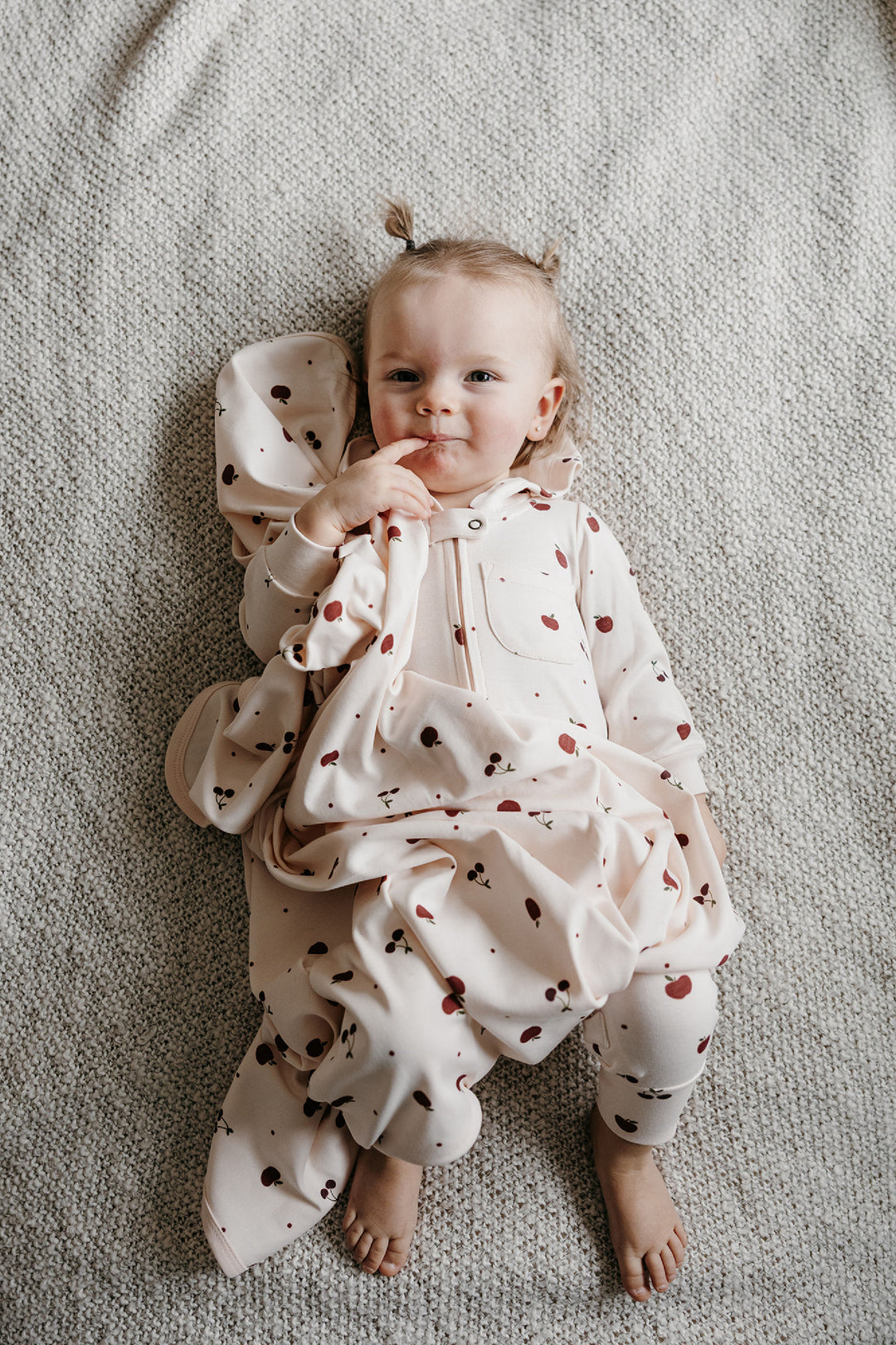 Child wearing Organic Hooded Zipper Romper in Cherry Apple.