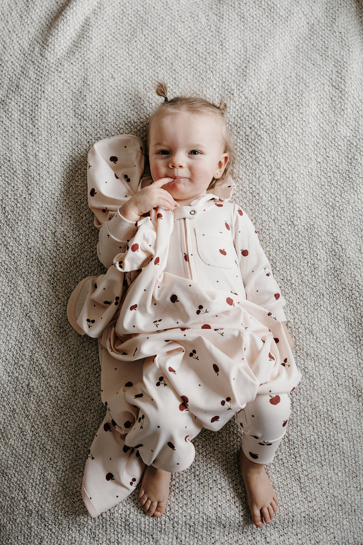 Child wearing Organic Hooded Zipper Romper in Cherry Apple.