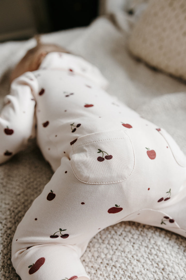 Child wearing Organic Hooded Zipper Romper in Cherry Apple.