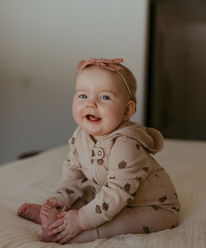 Child wearing Organic Hooded Zipper Romper in Little Acorn.