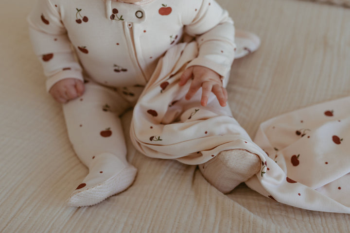 Child wearing Organic 2-Way Zipper Footie in Cherry Apple.