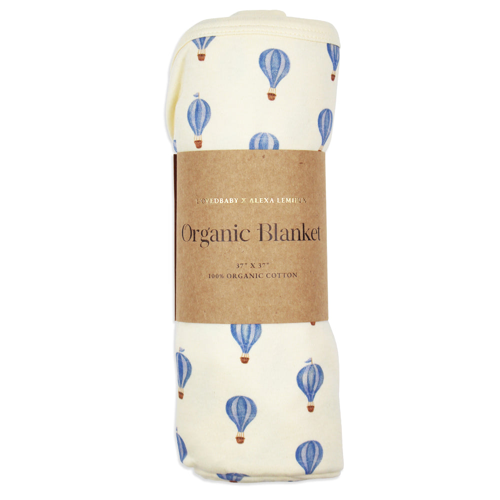 flat image of swaddle blanket in blue hot air balloon print, rolled neatly and placed inside kraft color card stock wrap sleeve