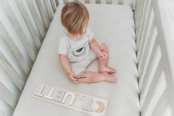 Child sleeping in crib. Mattress in the crib is fitted with our crib sheet in the Stone Dot color option.