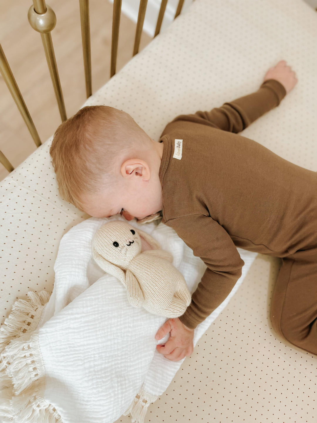 Child sleeping in crib. Mattress in the crib is fitted with our crib sheet in the Stone Dot color option.