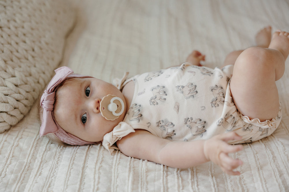 Child wearing Organic Bowtie Shoulder Bodysuit in Blush Boots.