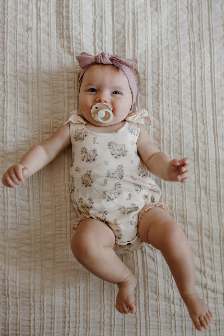 Child wearing Organic Bowtie Shoulder Bodysuit in Blush Boots.