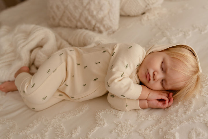 Child wearing Organic Zipper Romper in Buttercream Tree.