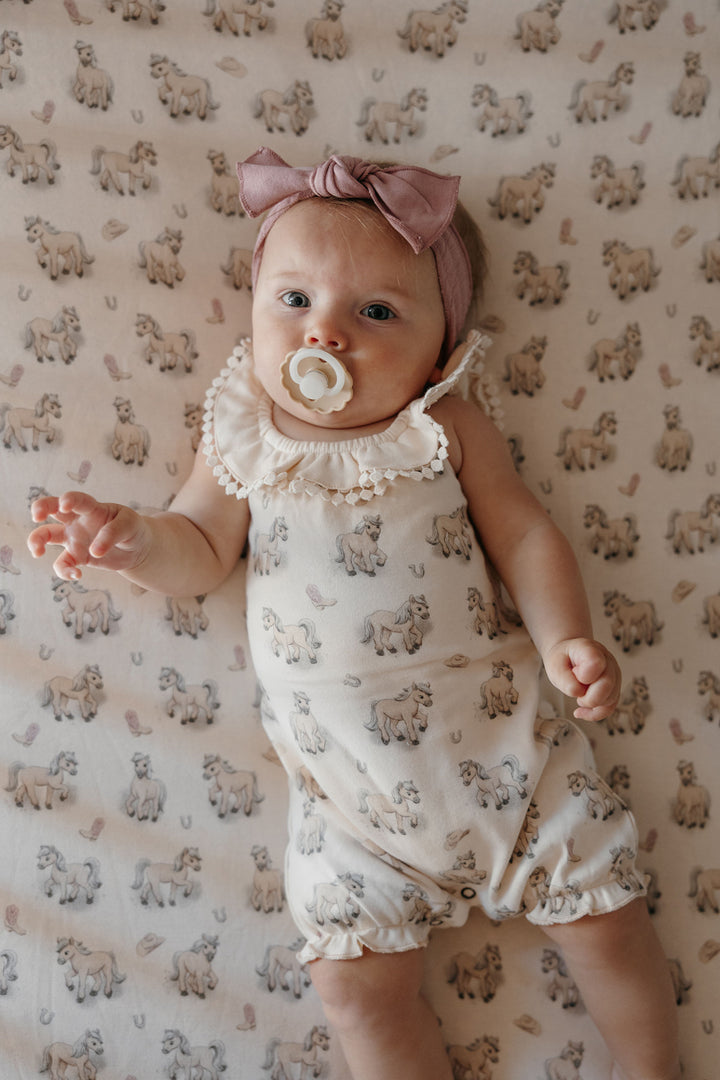 Child wearing Organic Bubble Romper in Blush Boots.