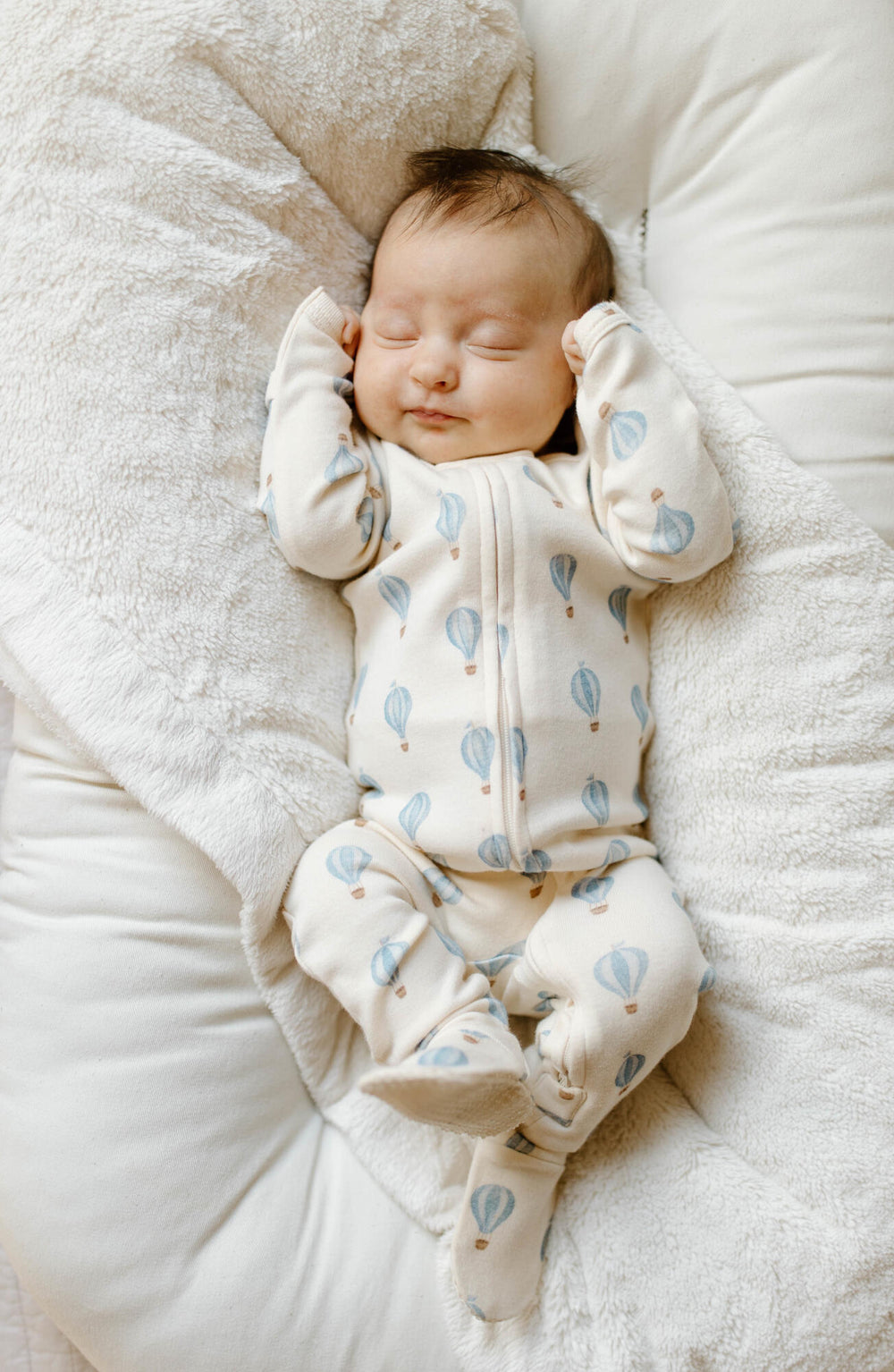 Baby lying on a bed wearing a patterned footie