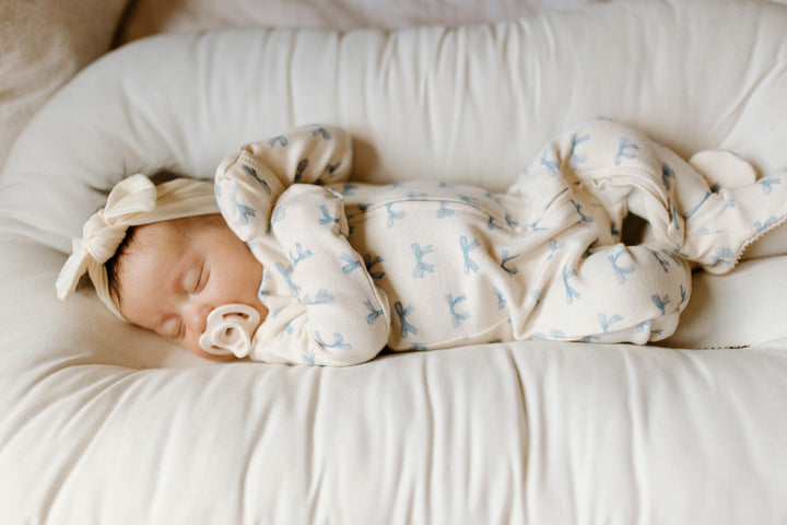 Baby footie with blue bow pattern on a white background