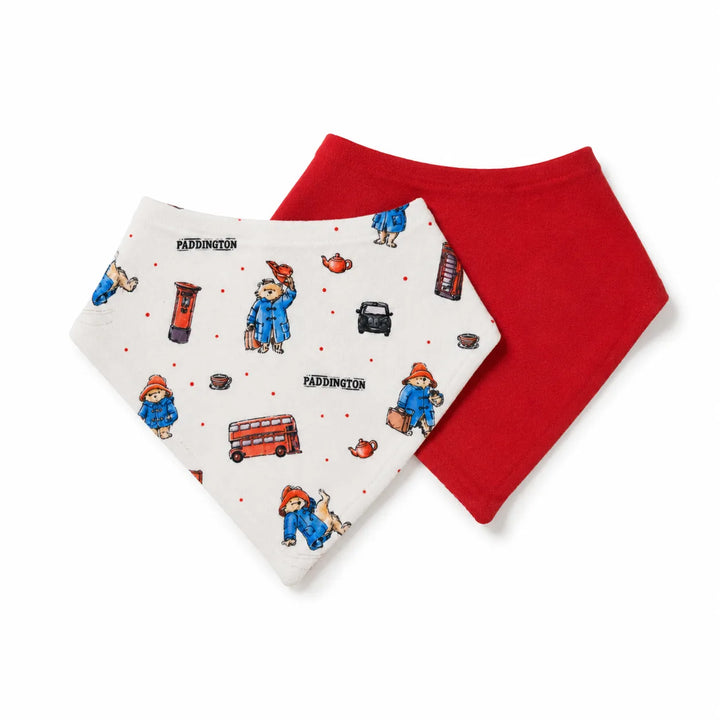 Two baby bandana bibs, one white with a colorful Paddington Bear pattern and one solid red, displayed on a clean white background.