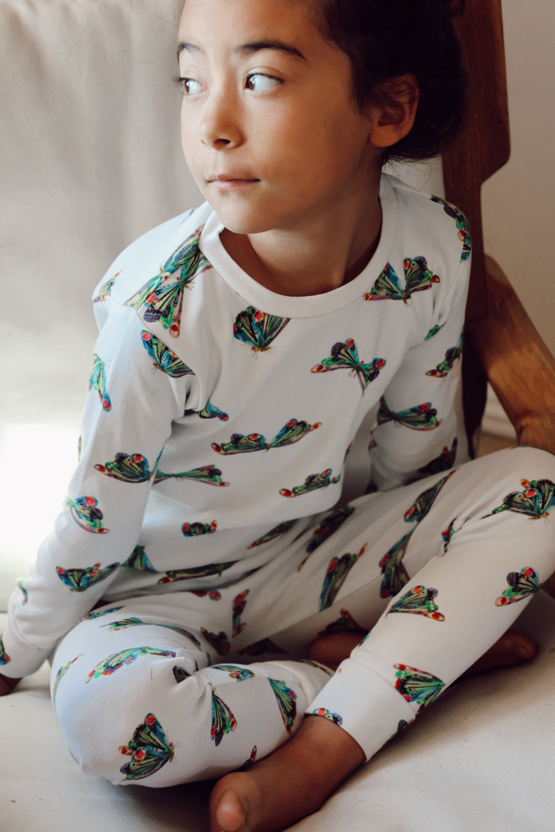 image of girl sitting on floor wearing the kids' pj set in butterfly print from very hungry caterpillar collection