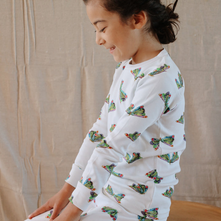 image of girl sitting on stool wearing the kids' pj set in butterfly print from very hungry caterpillar collection