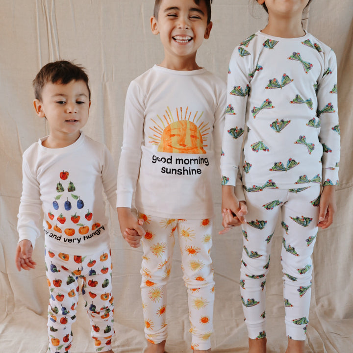 image of boy standing with siblings wearing the kids' pj set in sunny day print from very hungry caterpillar collection