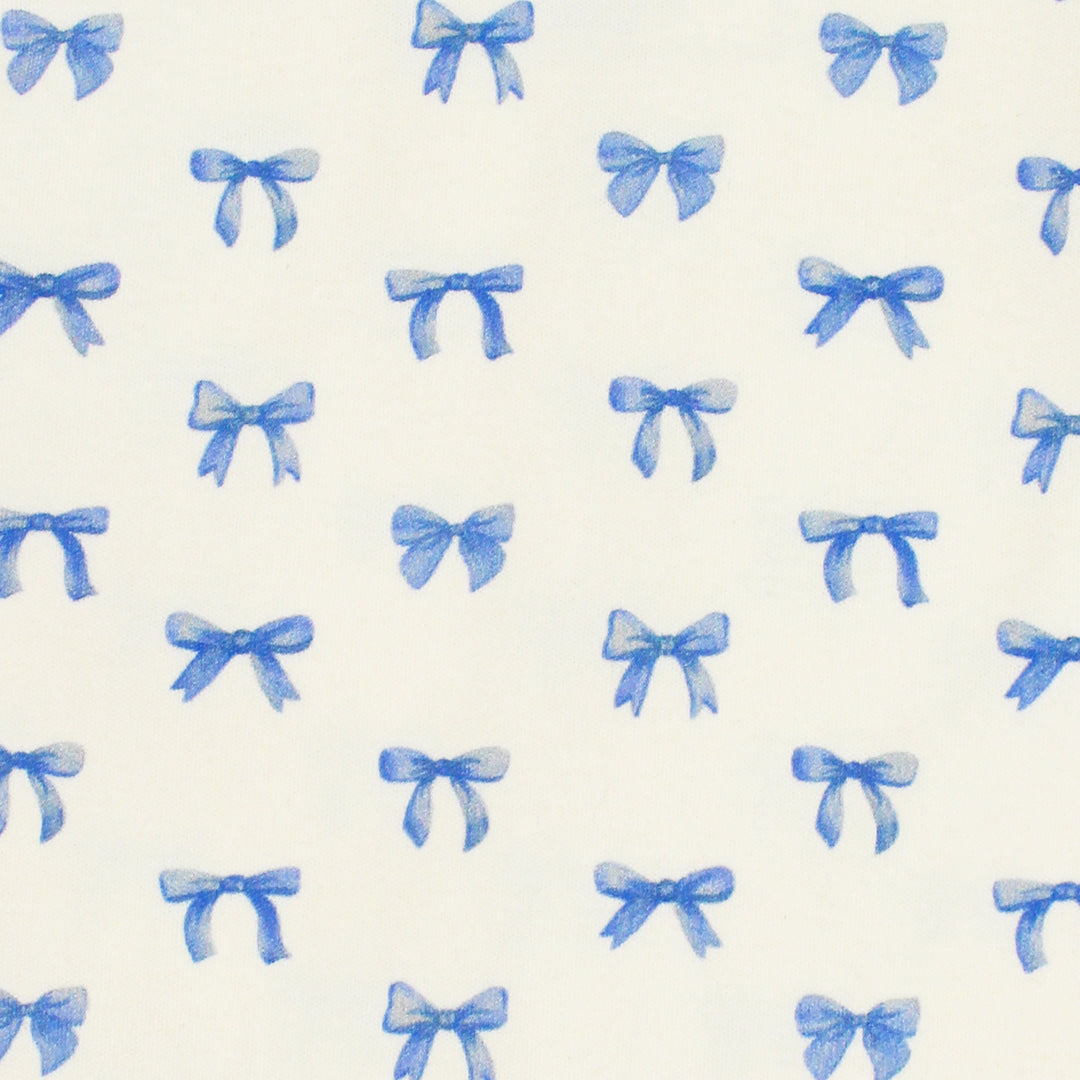close up swatch view of blue ribbon print on buttercream fabric