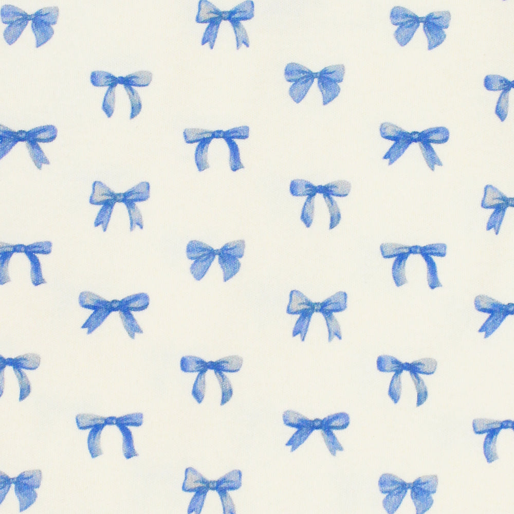 close up swatch view of blue ribbon print on buttercream fabric