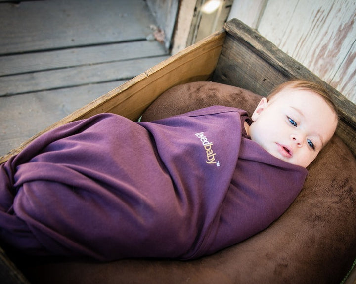 Child wearing Organic Swaddling Blanket in Eggplant.