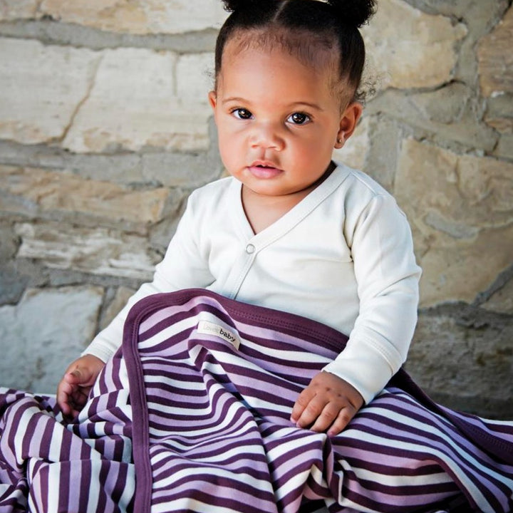 Child wearing Organic Swaddling Blanket in Eggplant Stripe.